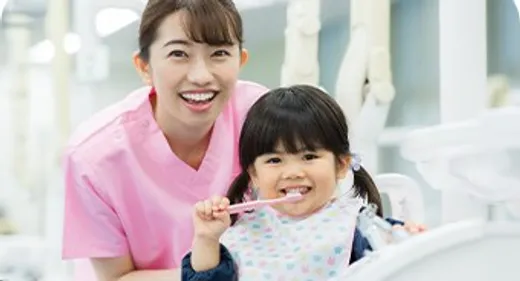 診療室で歯ブラシを持つ女の子とスタッフ