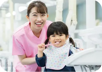 診療室で歯ブラシを持つ女の子とスタッフ