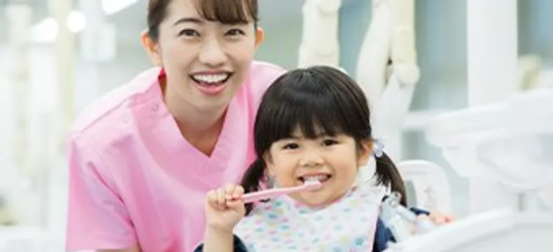 診療室で歯ブラシを持つ女の子とスタッフ