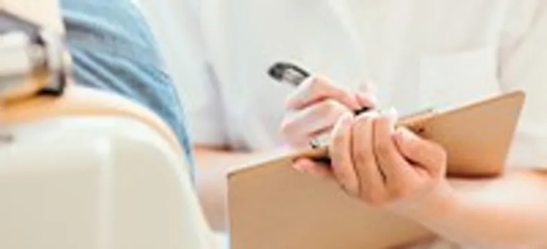 白衣のスタッフが問診内容を記入する様子