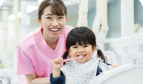 診療室で歯ブラシを持つ女の子とスタッフ